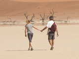A Couple Holds Hand While Walking Through a Sand Dune Park in Namibia Other